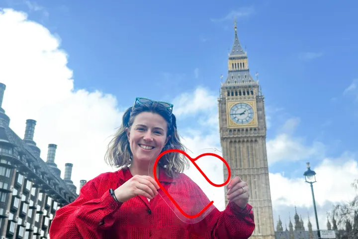A HeartLab team member holds a heart-shaped sign in front of the Elizabeth Tower in London